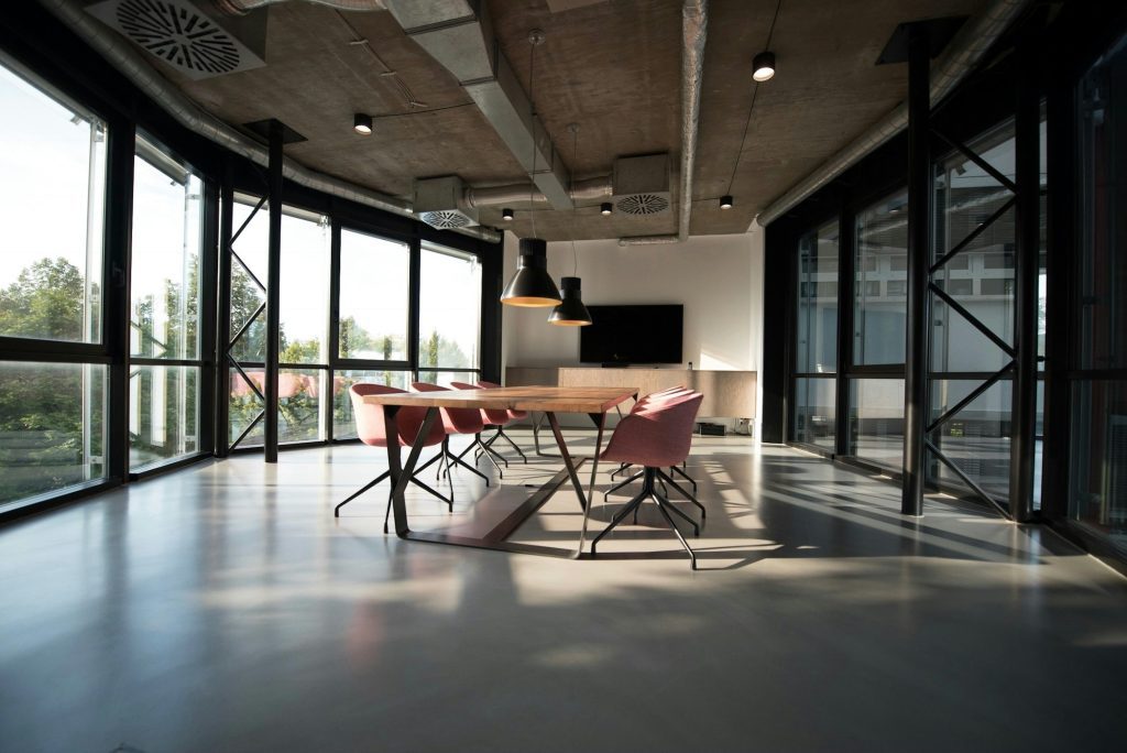 Sala de reunião ampla em um escritório moderno, com janelas de vidro e mesa de madeira